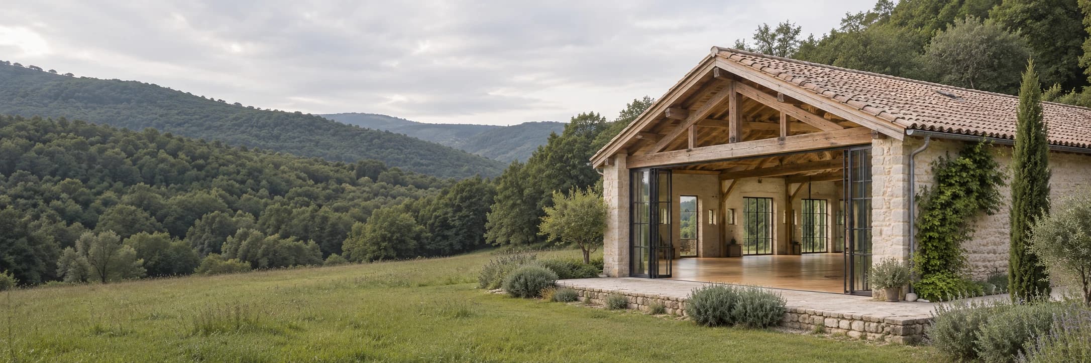 Salle de pratique en pierre et en bois ouverte sur des collines verdoyantes